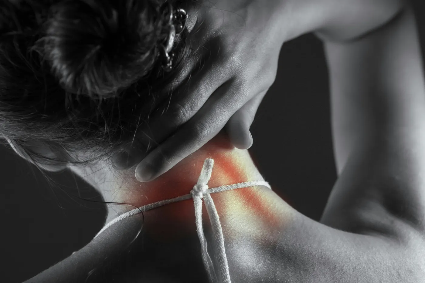 A person reaching back to hold the base of their neck